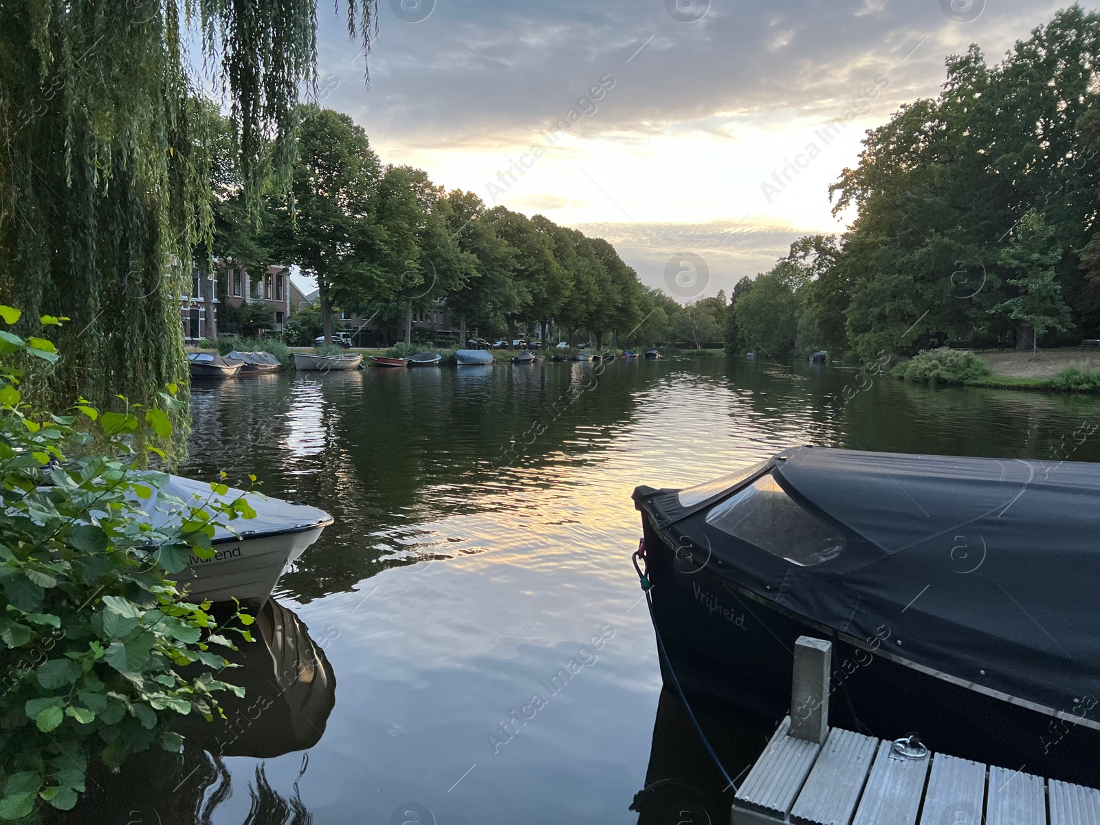 Photo of Leiden, Netherlands - August 21, 2022: Picturesque view of river with moored boats in evening