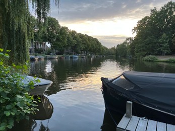 Leiden, Netherlands - August 21, 2022: Picturesque view of river with moored boats in evening