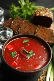 Stylish brown clay bowl with Ukrainian borsch on black table