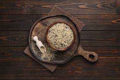 Photo of Raw unpolished rice on wooden table, top view