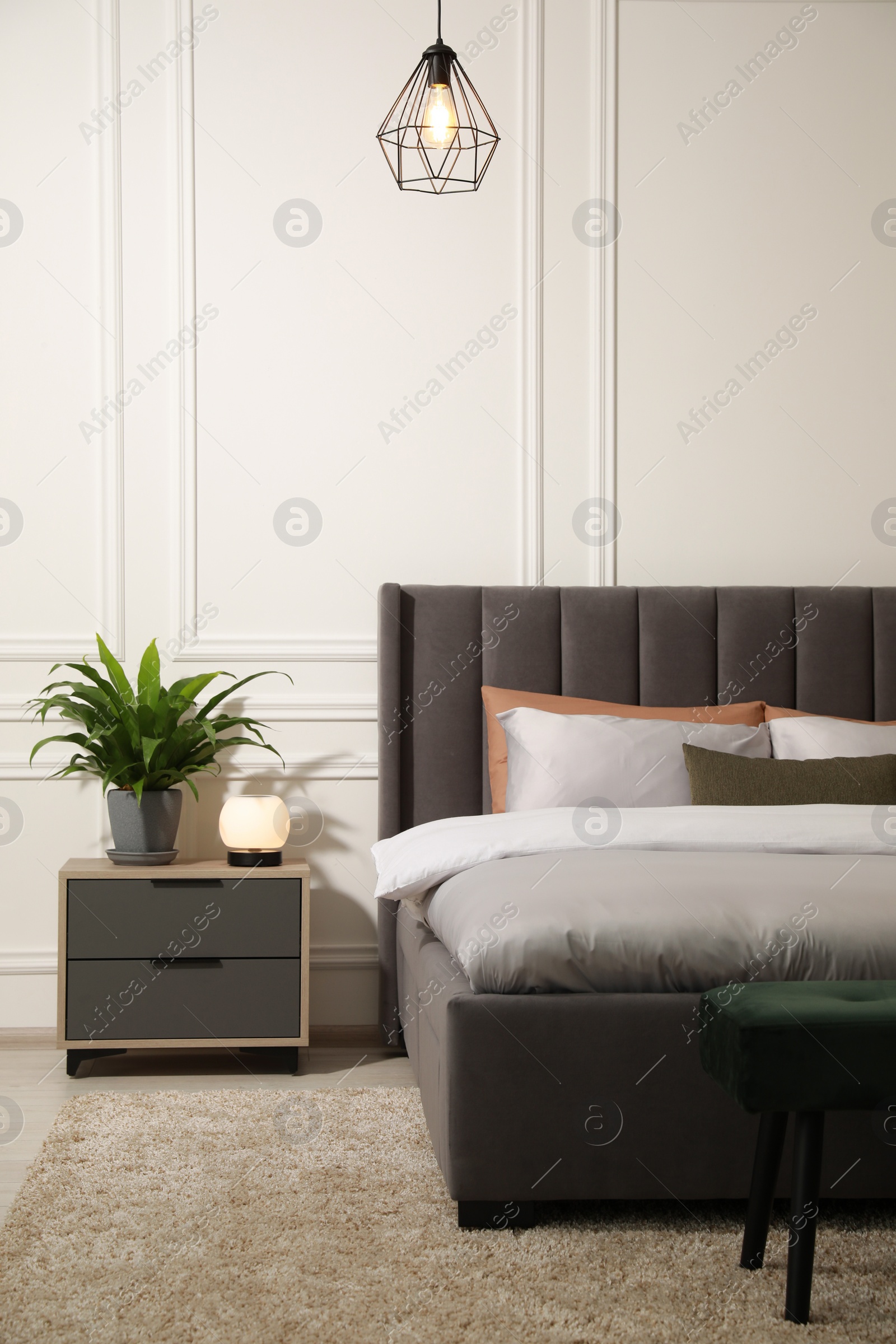 Photo of Stylish bedroom interior with large comfortable bed and ottoman