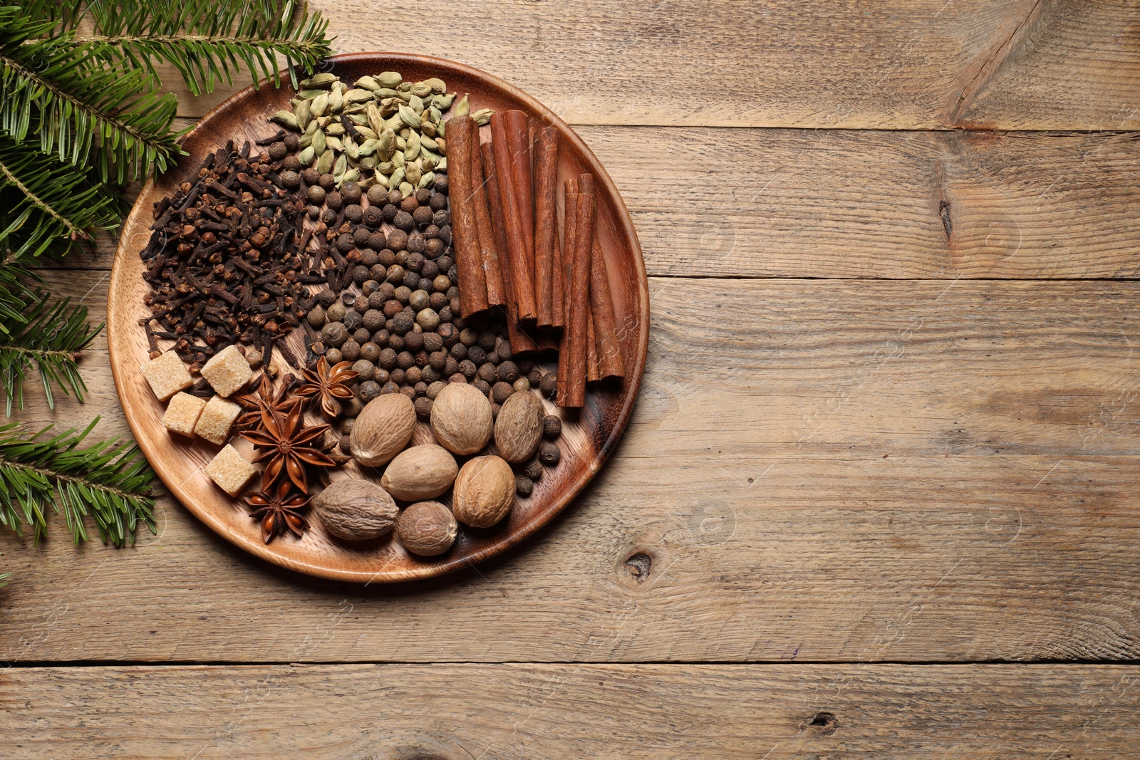 Photo of Different spices, nuts and fir branches on wooden table, flat lay. Space for text