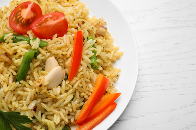 Photo of Tasty rice pilaf with vegetables on white wooden table, closeup