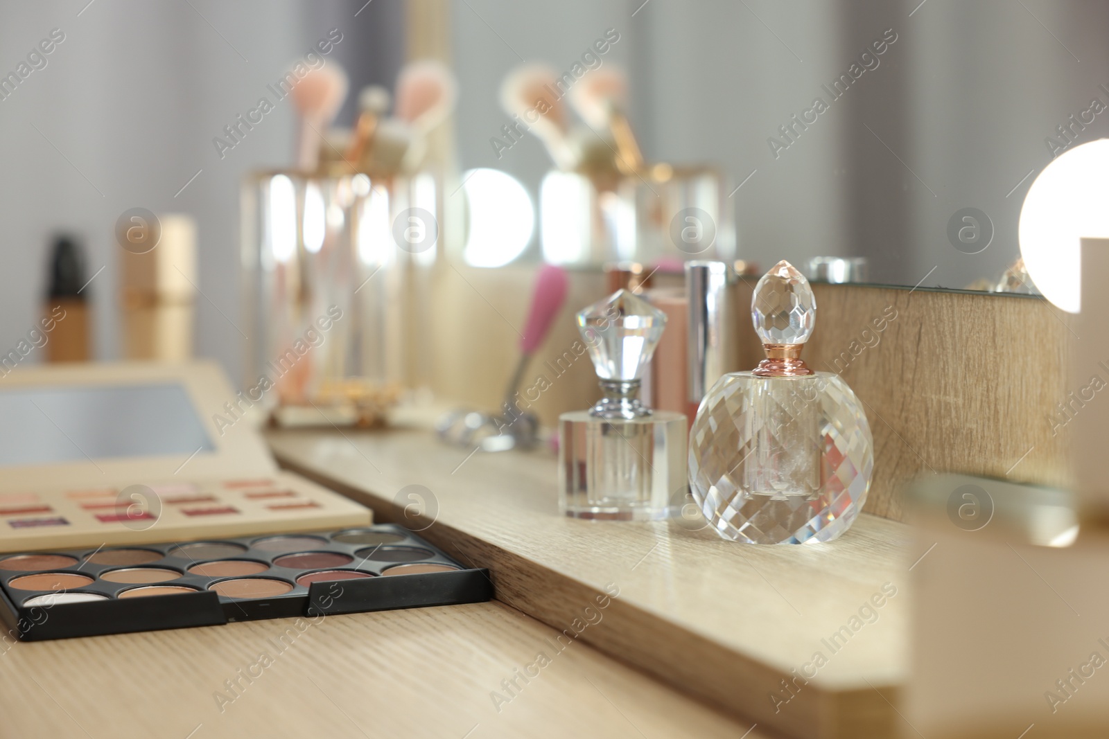 Photo of Cosmetic products and perfumes on wooden dressing table in makeup room