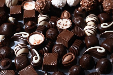 Many different delicious chocolate candies on metal surface, closeup view