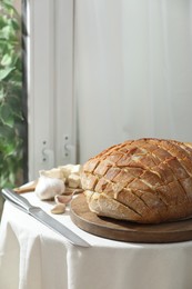 Freshly baked bread with tofu cheese, ingredients and knife on table indoors. Space for text