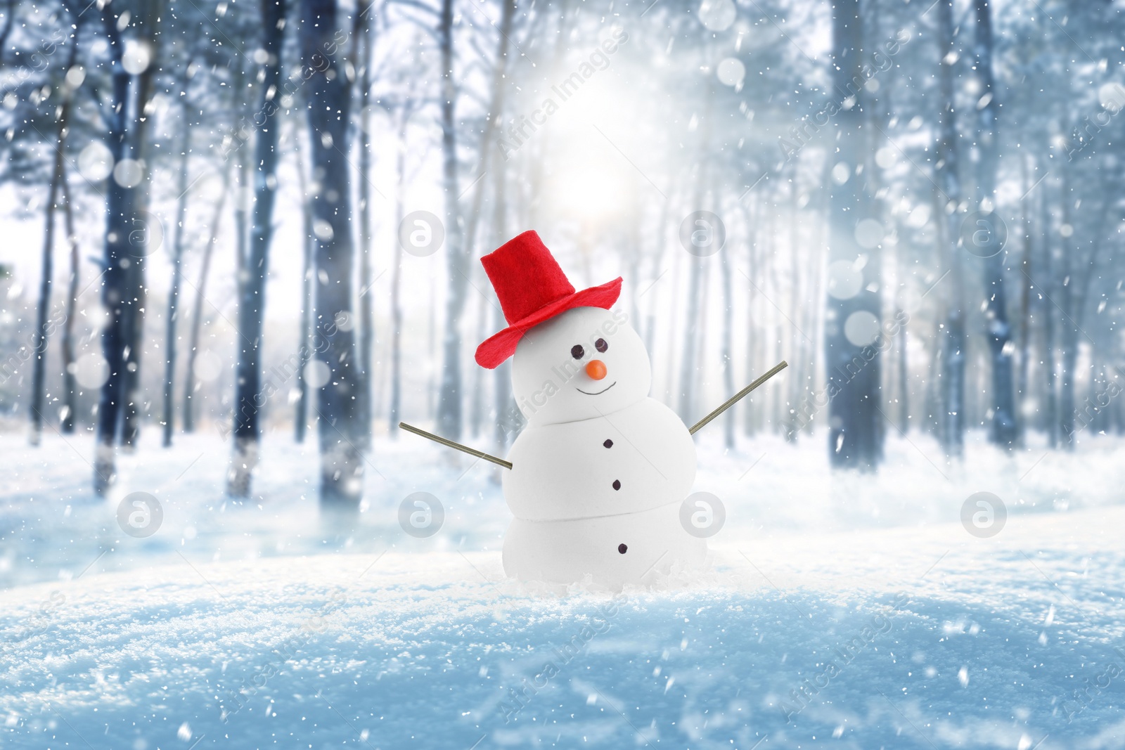 Image of Cute decorative snowman in red hat outdoors on snowy day