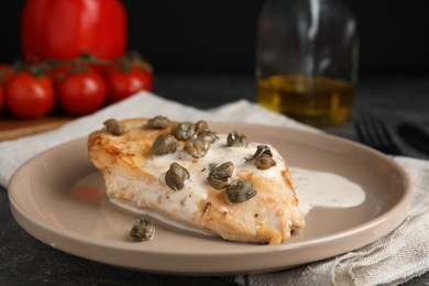 Photo of Delicious chicken fillet with capers and sauce served on grey table, closeup