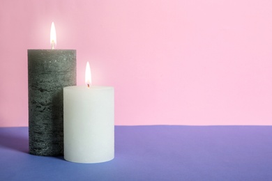 Decorative wax candles on table against color background