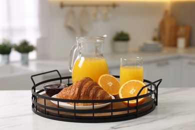 Breakfast served in kitchen. Tray with fresh croissant, jam and orange juice on white table