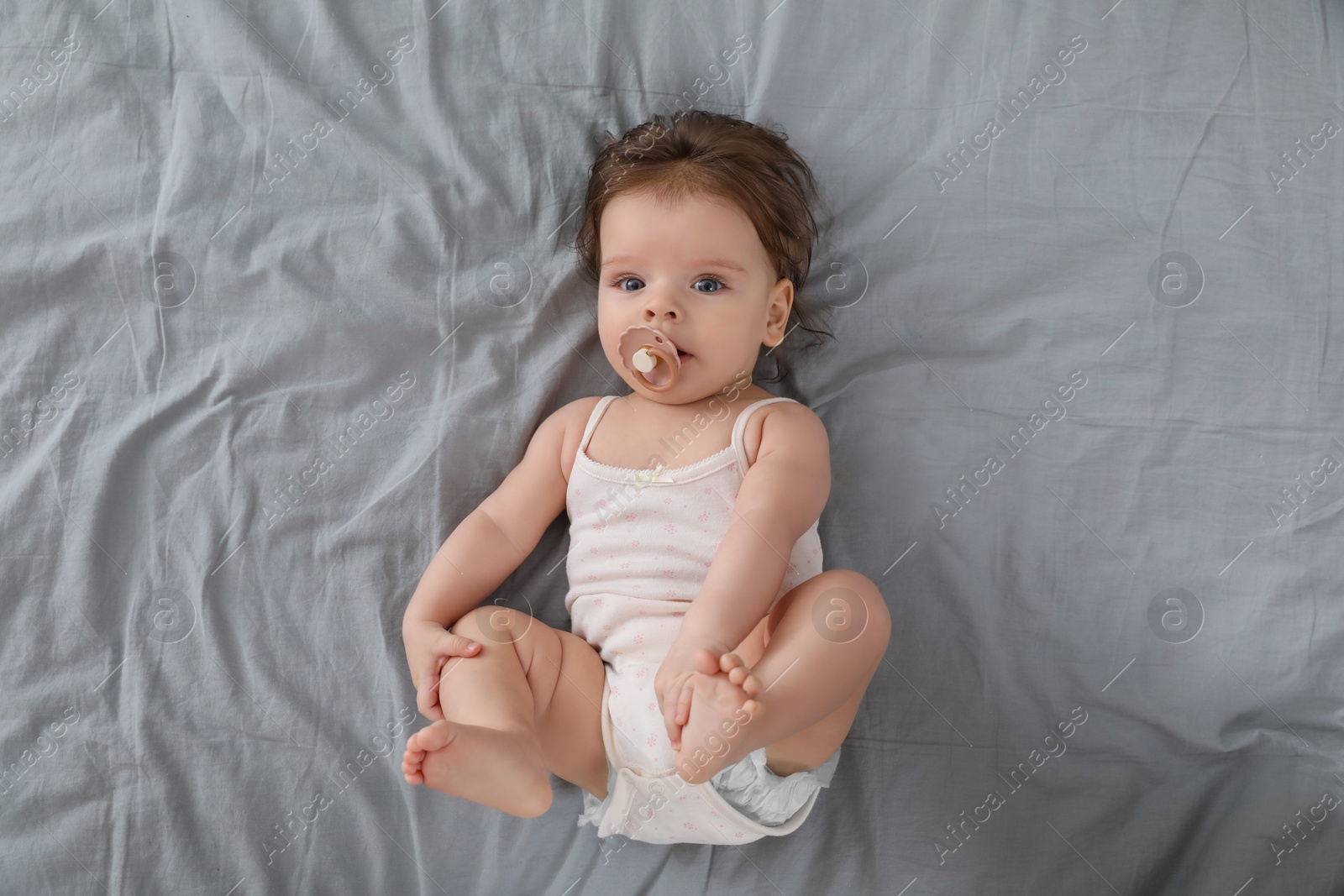 Photo of Cute little baby with pacifier on bed, top view