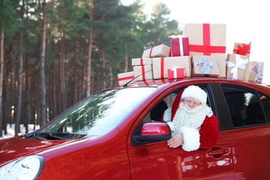 Authentic Santa Claus driving car with gift boxes, view from outside