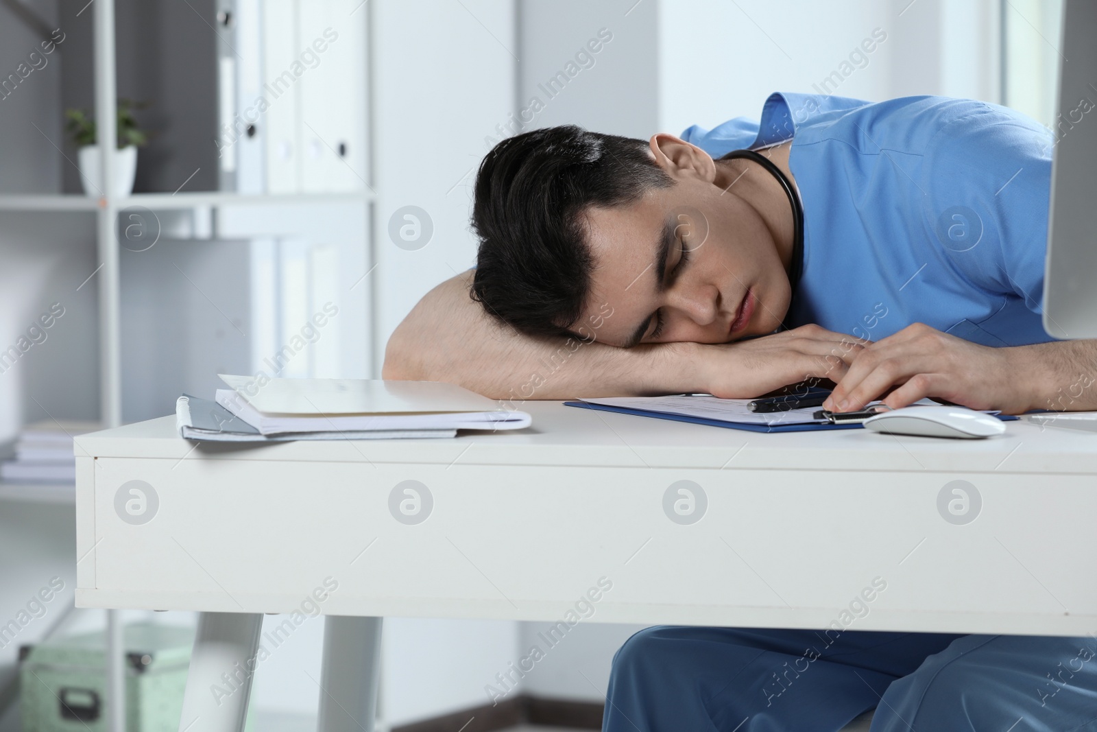 Photo of Exhausted doctor sleeping at workplace in hospital