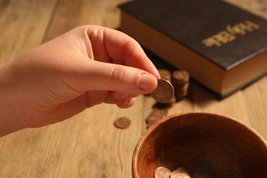 Donate and give concept. Woman putting coin into bowl at table, closeup