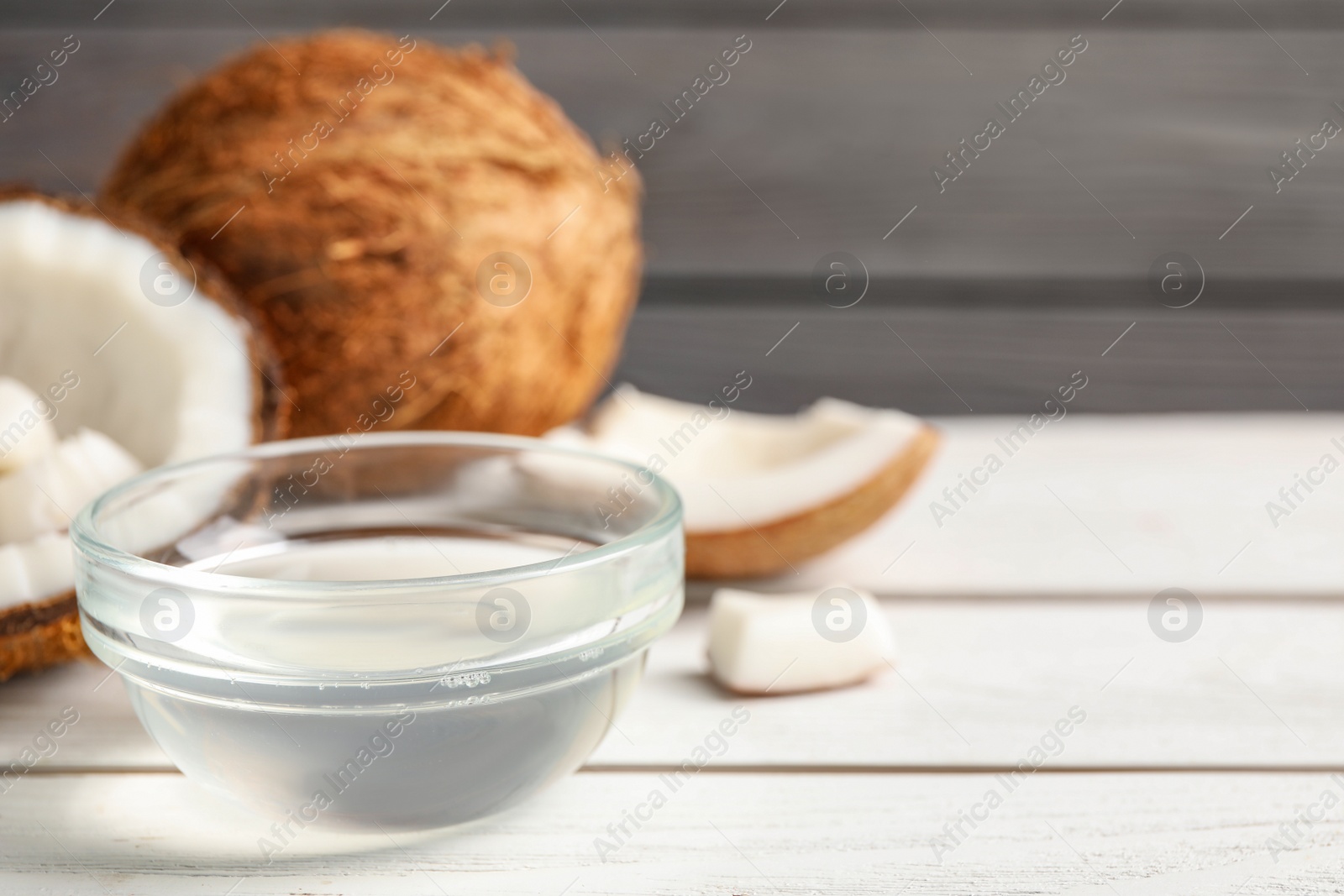 Photo of Coconut oil on white wooden table, space for text