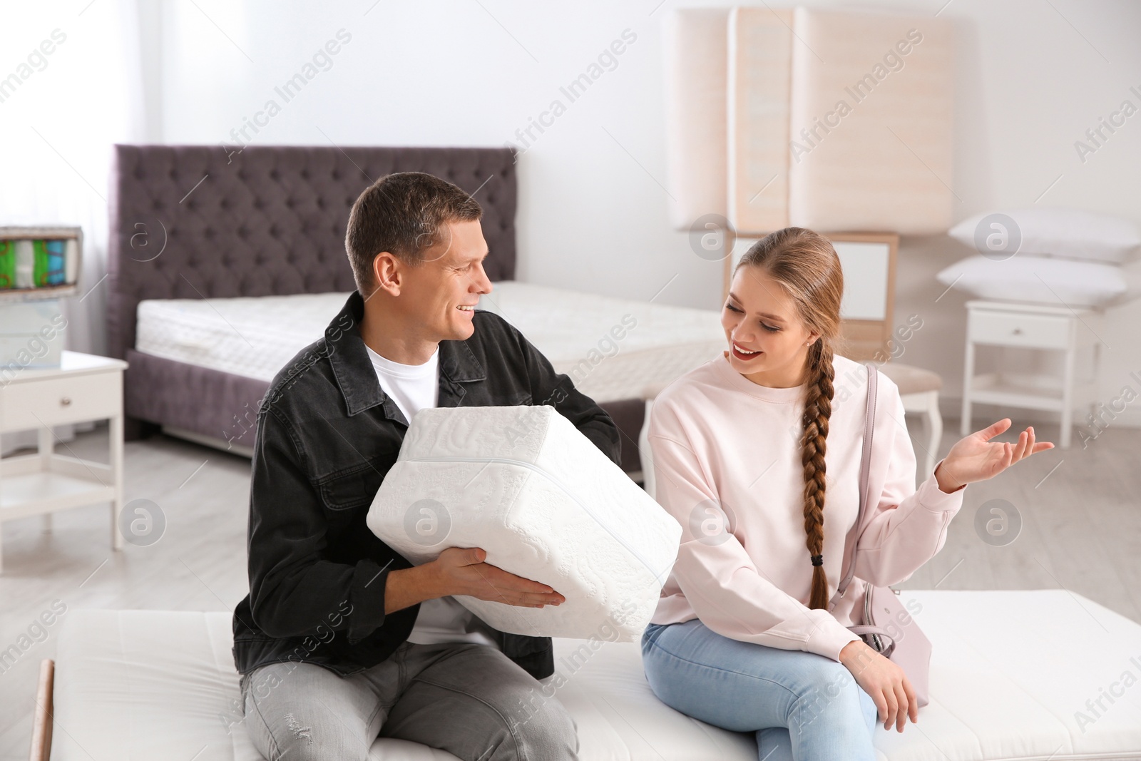 Photo of Happy couple choosing mattress in furniture store