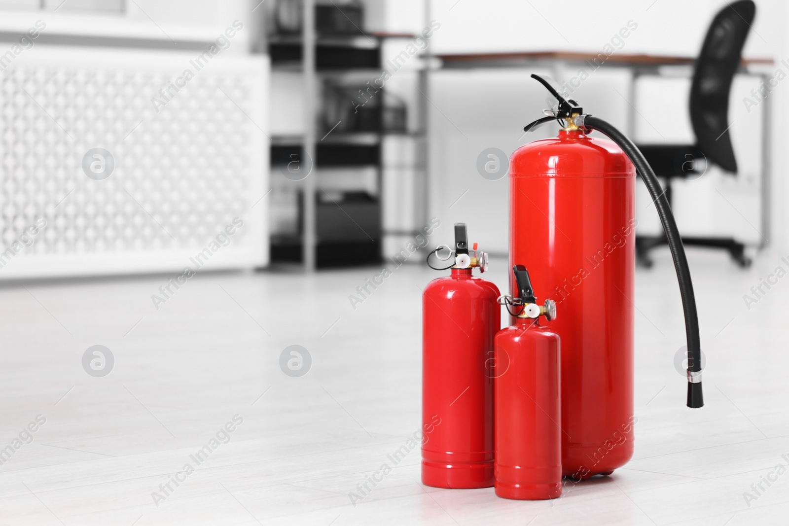 Photo of Fire extinguishers on floor indoors, space for text