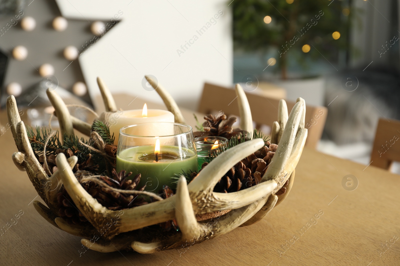 Photo of Burning scented conifer candles with Christmas decor  on wooden table indoors