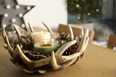 Photo of Burning scented conifer candles with Christmas decor  on wooden table indoors