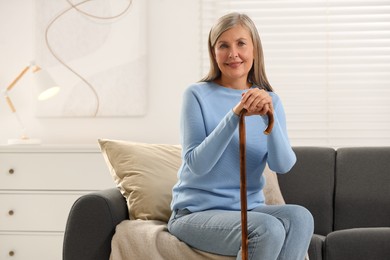 Photo of Mature woman with walking cane on sofa at home