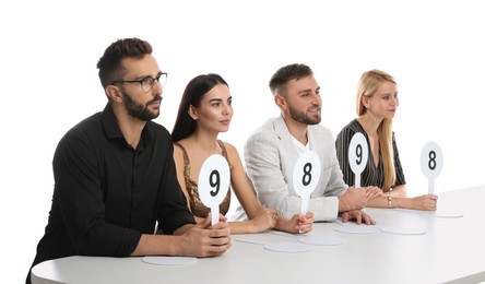 Panel of judges holding different score signs at table on white background