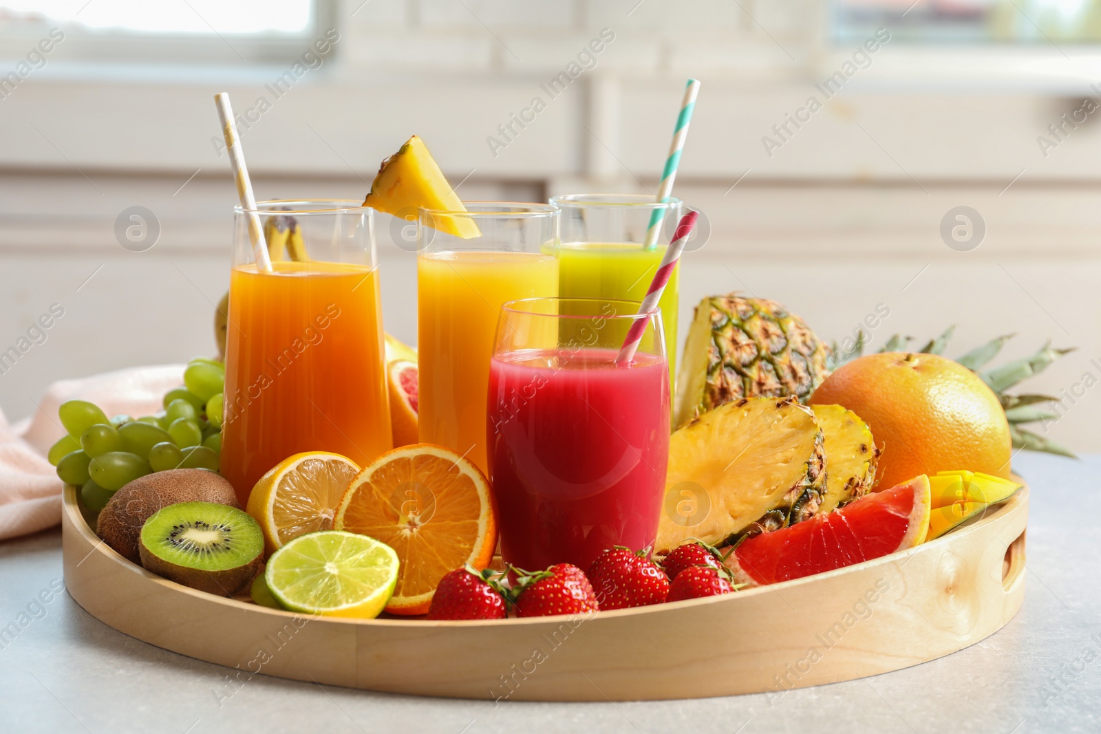 Photo of Wooden tray with glasses of different juices and fresh fruits on table