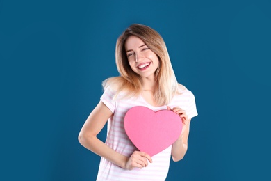 Portrait of pretty woman with heart shaped gift box on color background