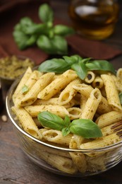 Photo of Delicious pasta with pesto sauce and basil on wooden table, closeup