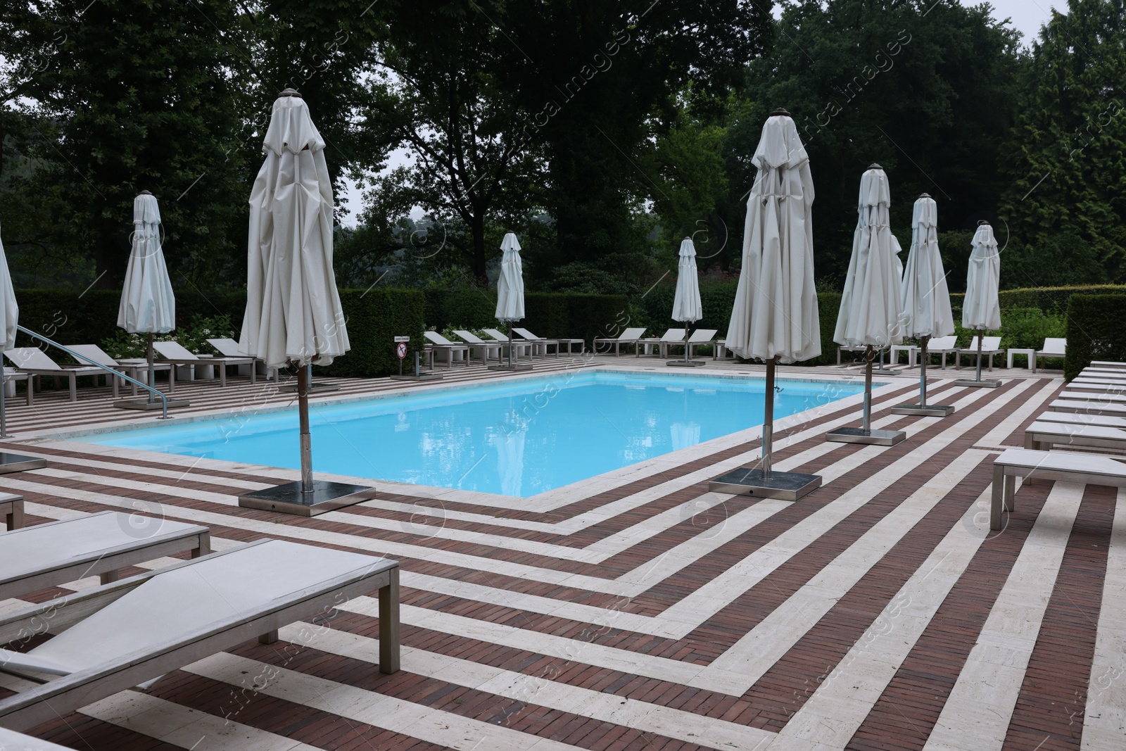 Photo of Many sunbeds and umbrellas near outdoor swimming pool