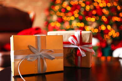 Photo of Christmas gifts on table against blurred festive lights