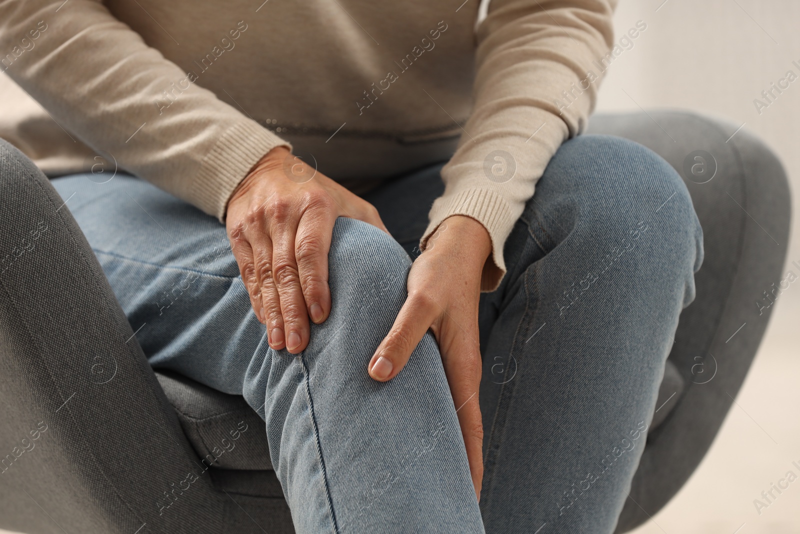 Photo of Mature woman suffering from knee pain in armchair, closeup. Rheumatism symptom