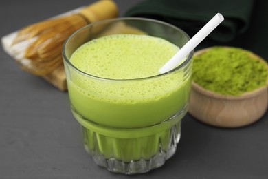 Photo of Glass of tasty matcha smoothie with straw on grey table, closeup