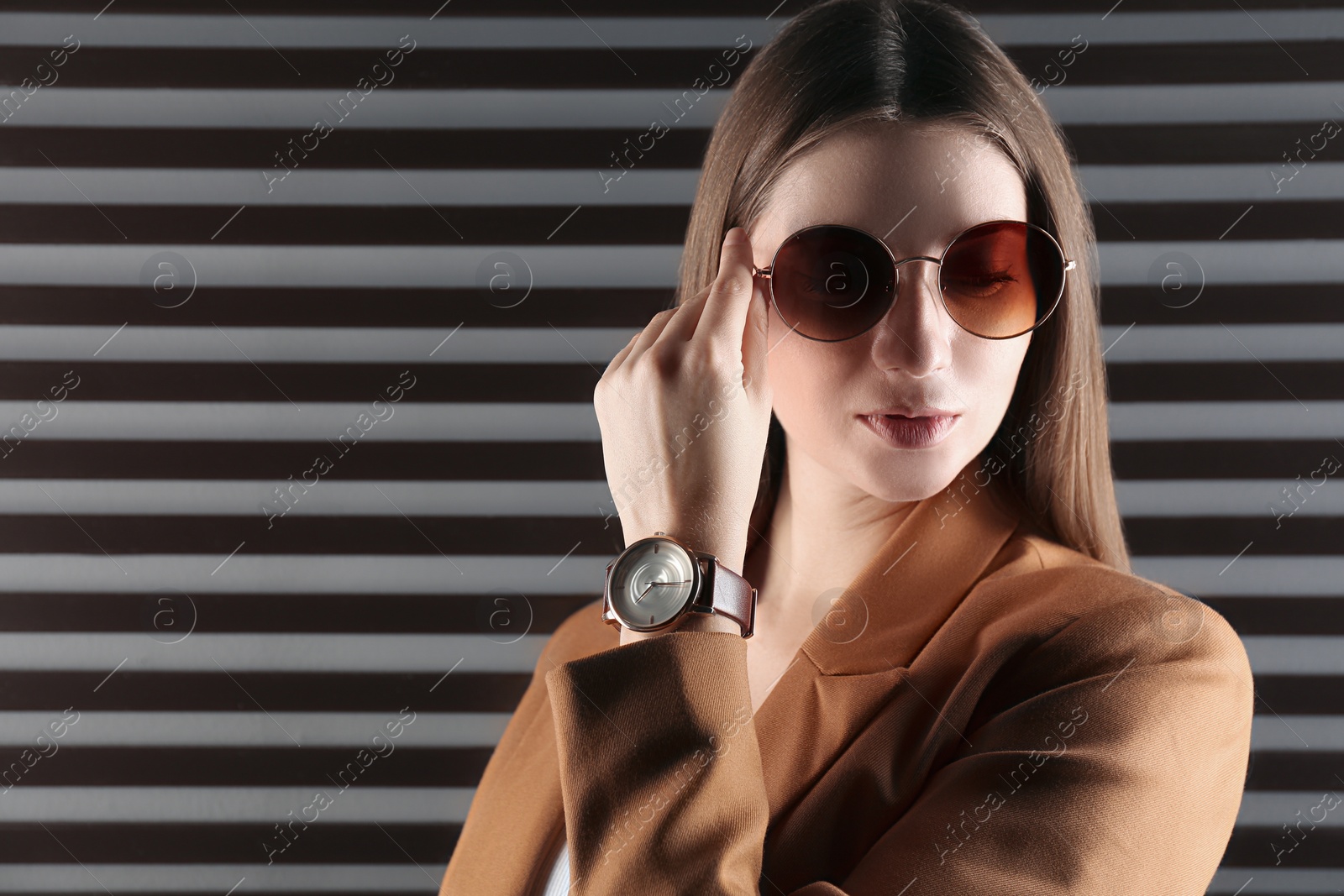 Photo of Woman wearing luxury wristwatch on dark background. Space for text