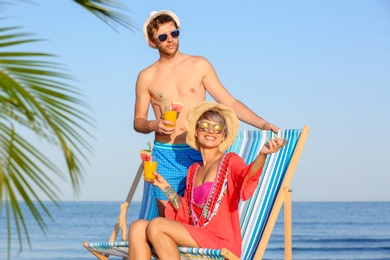 Photo of Young couple with exotic cocktails on beach
