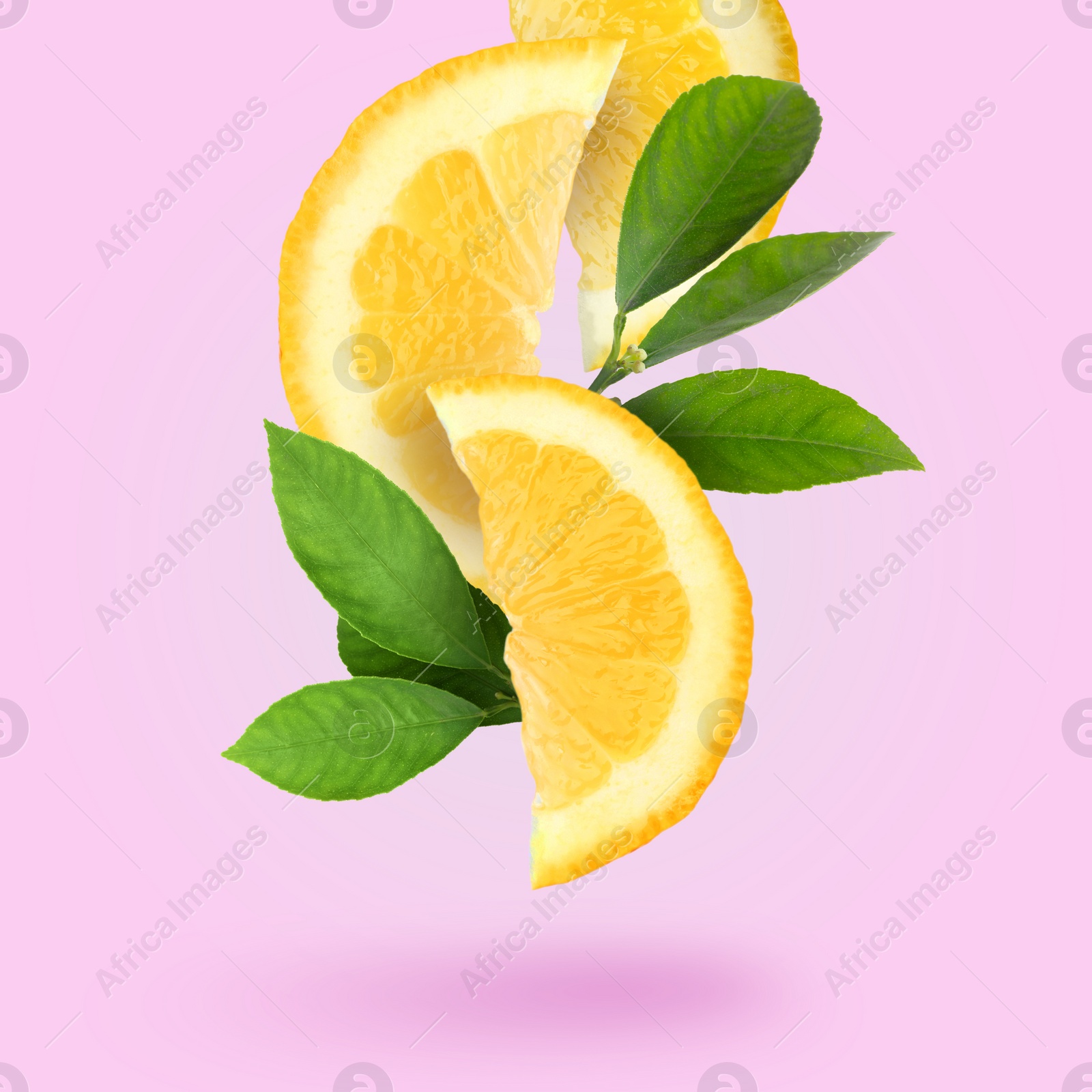 Image of Cut fresh lemon with green leaves falling on pink background