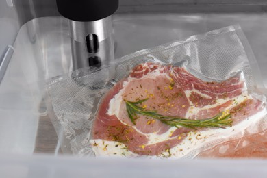 Photo of Thermal immersion circulator and vacuum packed meat in box, closeup. Sous vide cooking