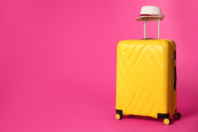 Photo of Stylish suitcase with hat on color background. Space for text