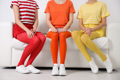 Photo of Women wearing bright tights sitting on sofa indoors, closeup