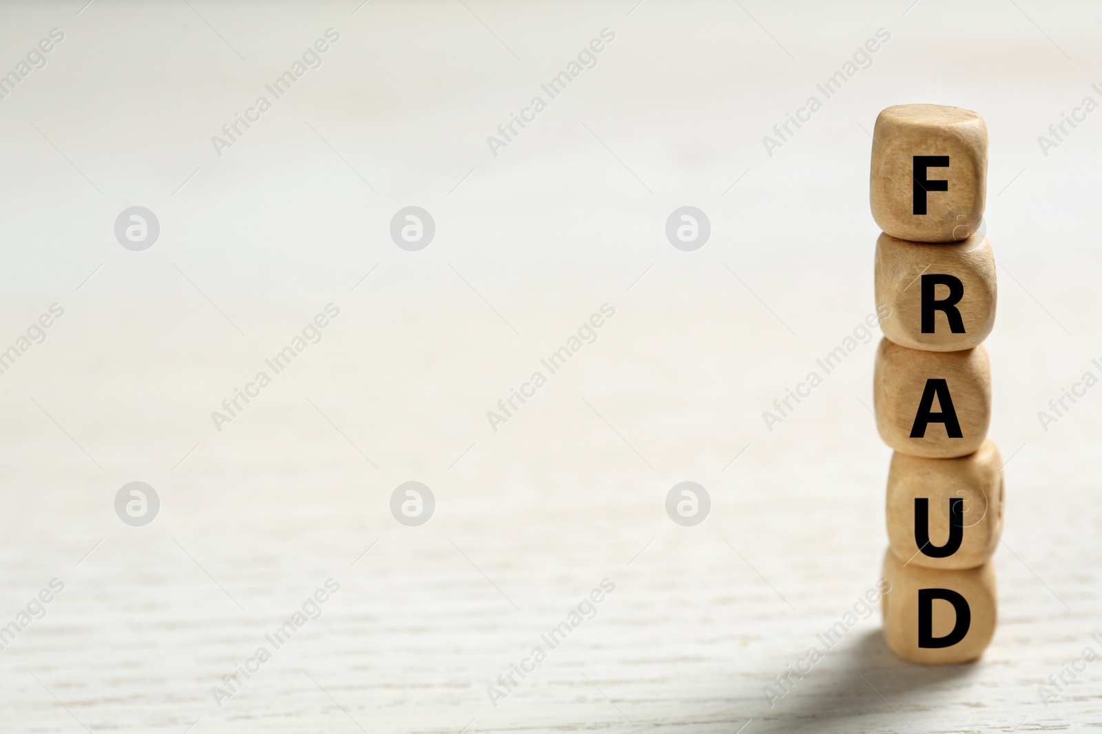 Photo of Word Fraud of cubes with letters on white wooden background. Space for text