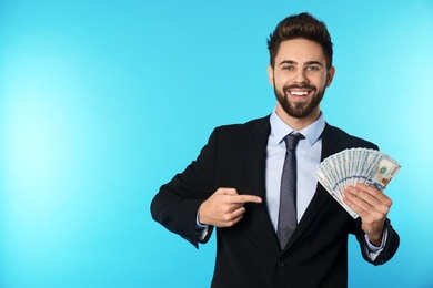 Portrait of happy young businessman with money on color background. Space for text