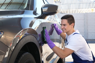 Worker cleaning automobile with rag at car wash