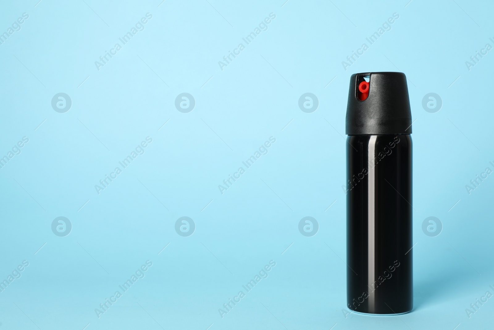 Photo of Bottle of gas pepper spray on light blue background. Space for text