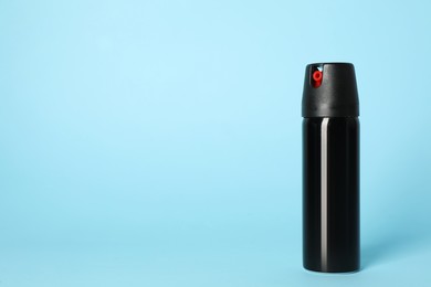 Photo of Bottle of gas pepper spray on light blue background. Space for text