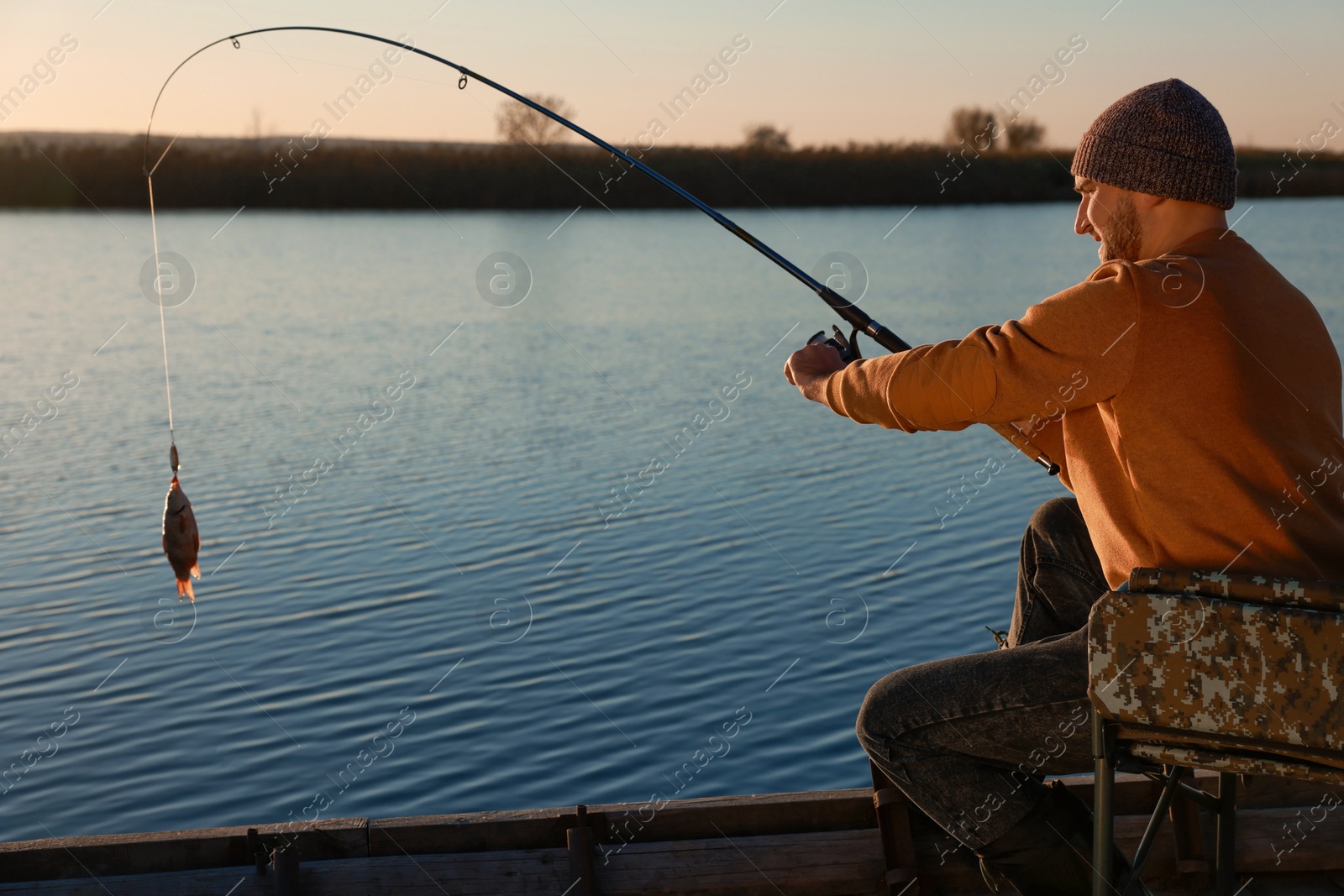 Photo of Fisherman catching fish with rod at riverside