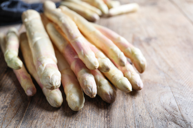 Photo of Pile of fresh white asparagus on wooden table, closeup