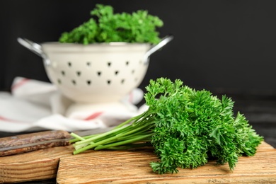 Photo of Cutting board with fresh green parsley and knife on wooden table