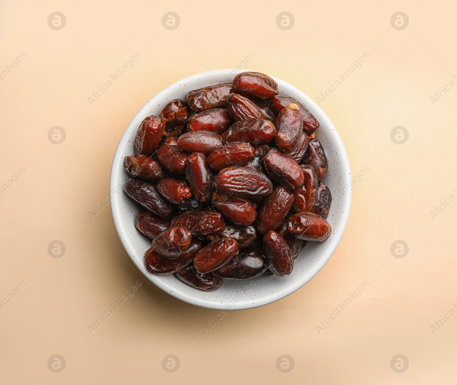 Photo of Bowl with sweet dried date fruits on color background, top view