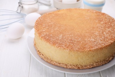 Plate with delicious sponge cake on white wooden table, closeup