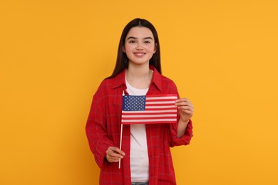 4th of July - Independence Day of USA. Happy girl with American flag on yellow background