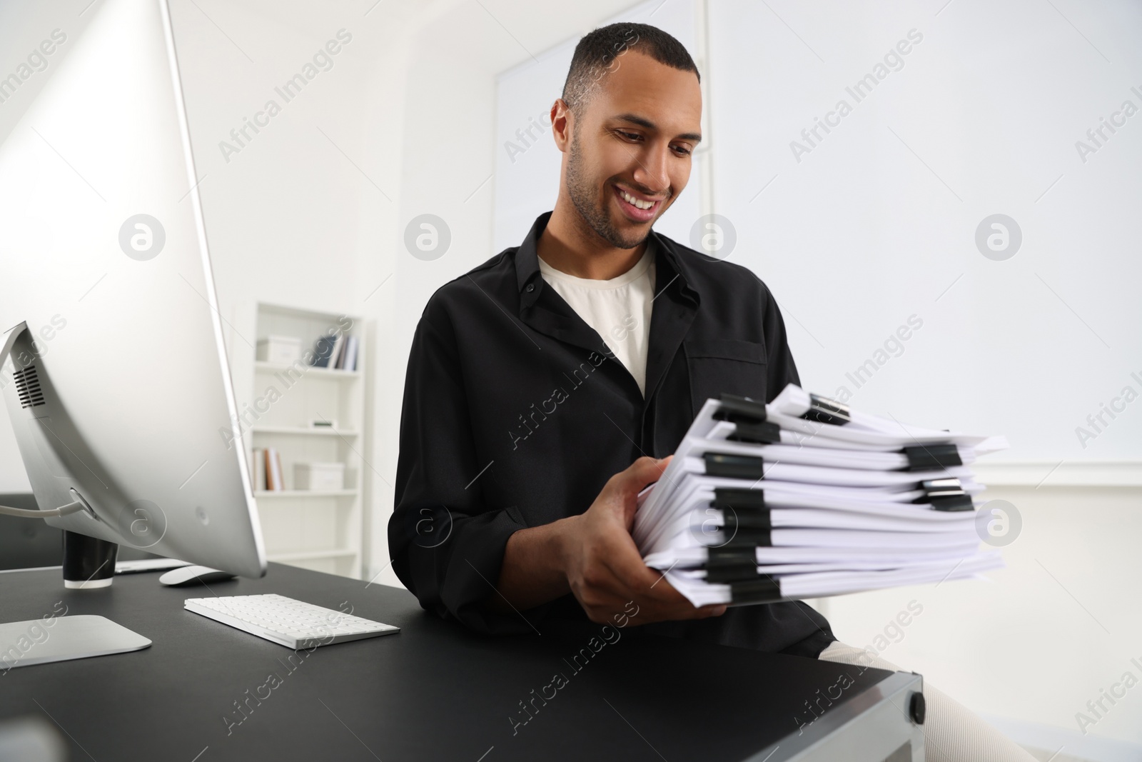 Photo of Happy man with documents at grey table in office